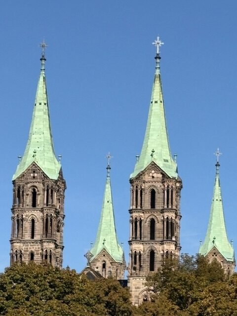 Die vier Türme des Bamberger Doms mit grüner Kupferpatina vor blauem Himmel